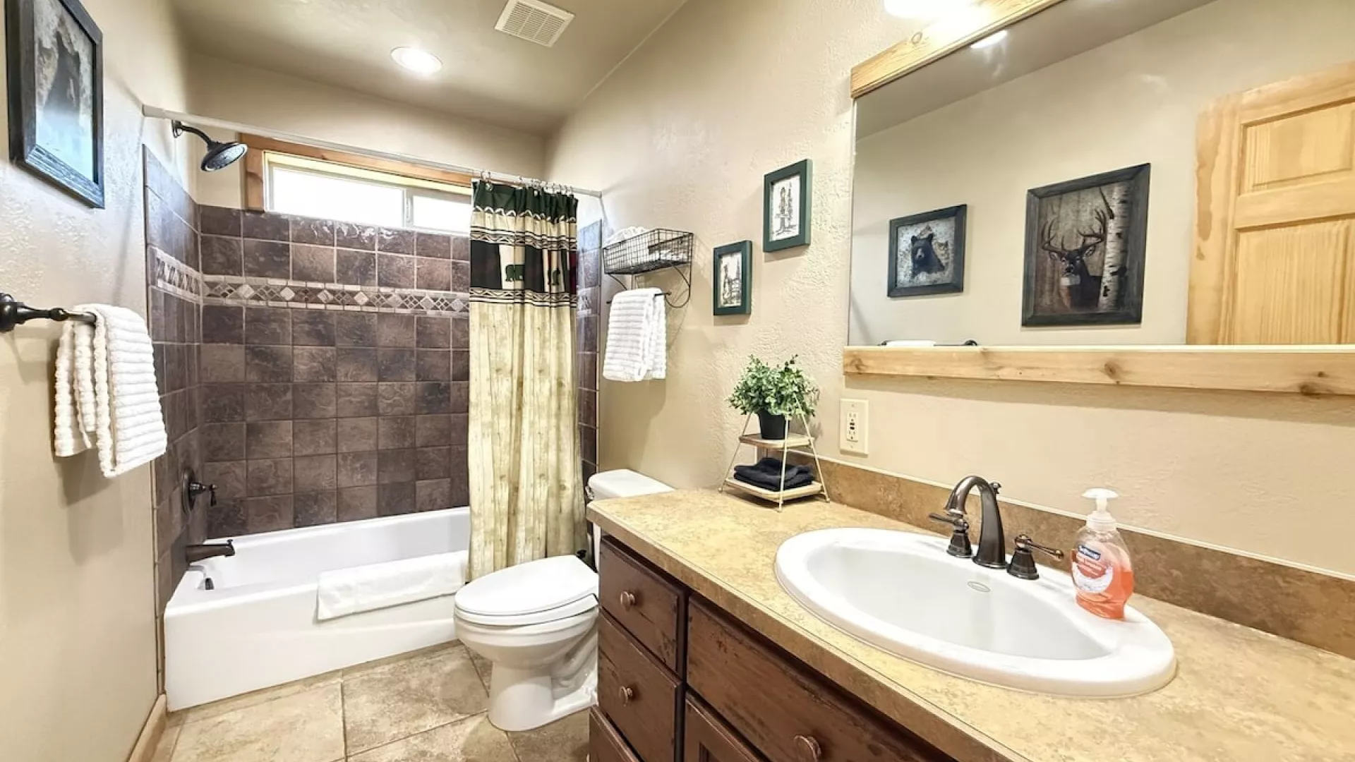 Main level bathroom with shower tub combo, toilet, and sink vanity. Bathroom is equipped with clean towels, toilet paper, shampoo, conditioner, and body wash.