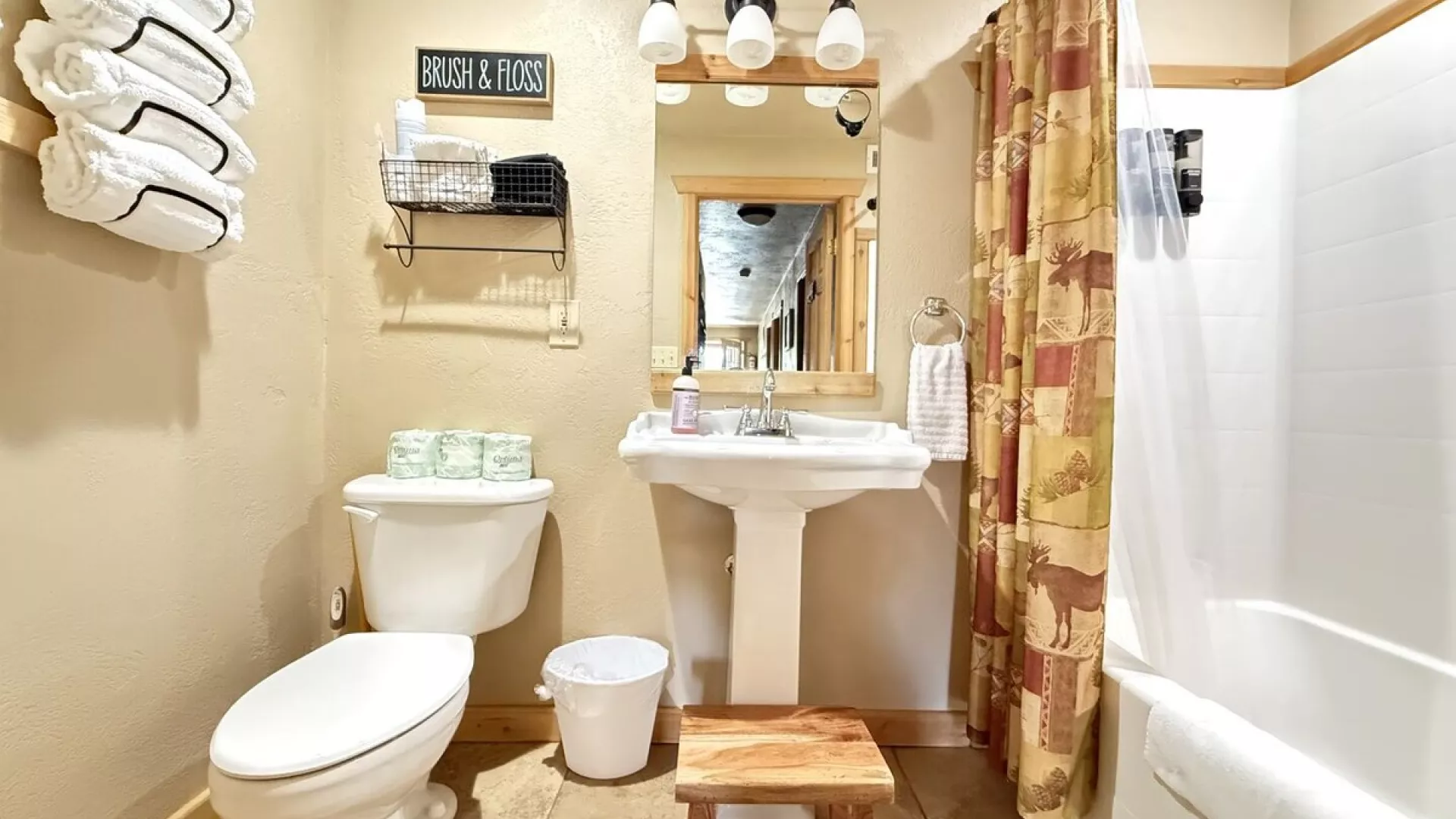 Downstairs bathroom with shower tub combo, toilet, and sink. Towels, shampoo, conditioner, and body wash are provided.