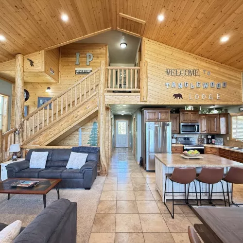Access to the third level is up the stairs. The open kitchen blends seamlessly into the cabin's cozy living area, creating a welcoming space perfect for gathering and unwinding.