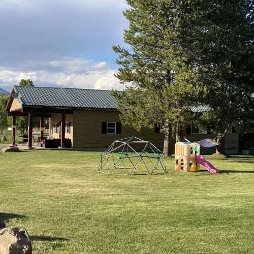 Large grass area and small play set is located adjacent to the cabin.