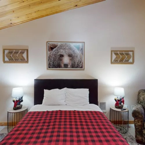 The bedroom has a queen bed, additional seating, and a large window to enjoy the beautiful landscape.